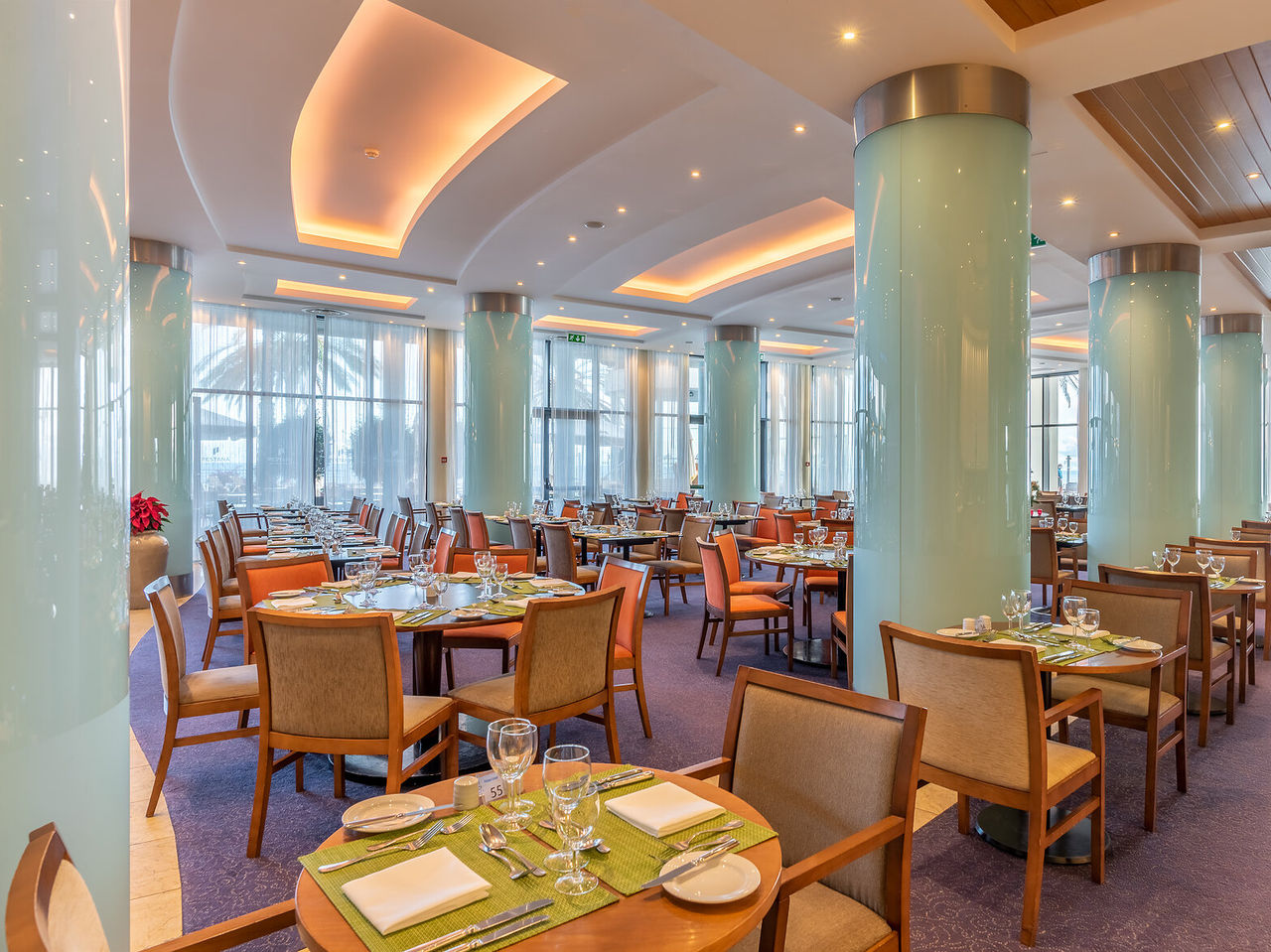 The Restaurant Atrium at a 5-star Funchal hotel has a large hall, blue columns and tables