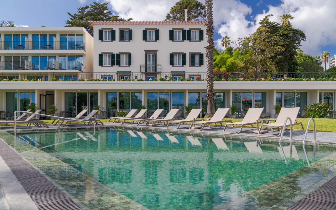View of the outdoor pool at Pestana Quinta Perestrello, a Charming Hotel in Madeira, with the building behind