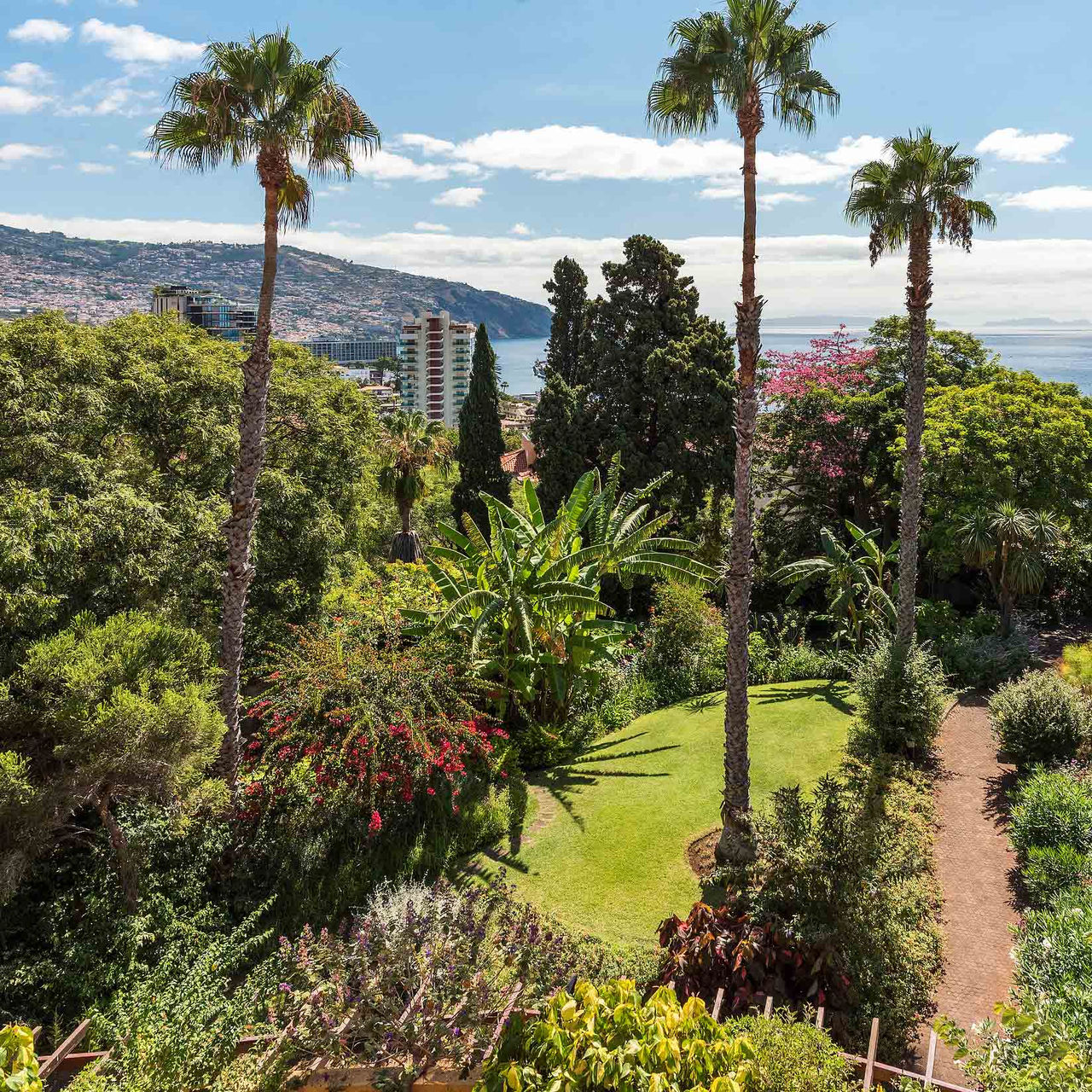 View of the pool, building, and palm trees at Pestana Village, a romantic hotel in Funchal, Madeira