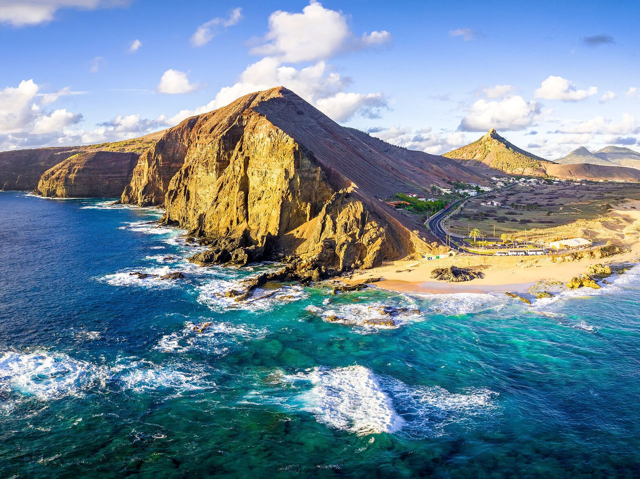Explore Hotels in Porto Santo with an aerial view of rocky cliffs, turquoise waves and coastal roads