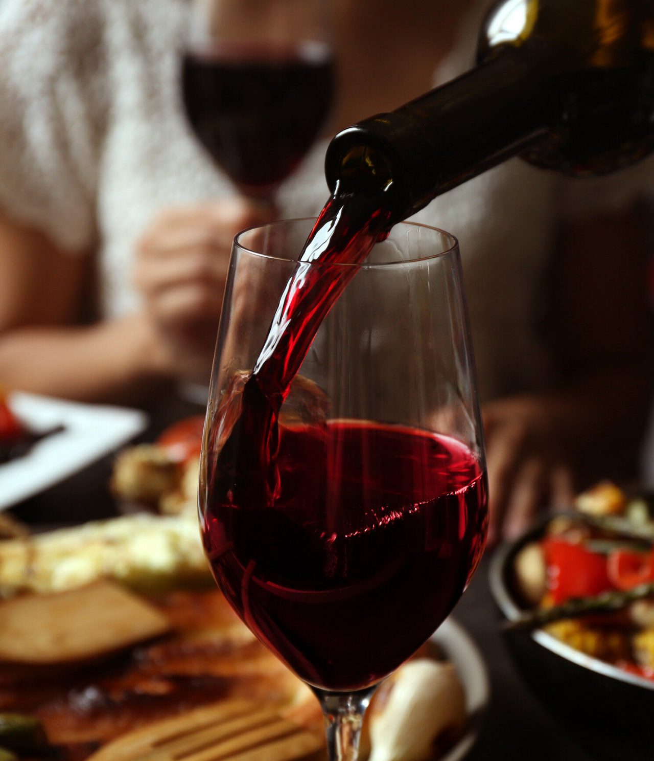 Discover Hotels in Porto featuring red wine poured into a glass beside a softly lit dining table scene