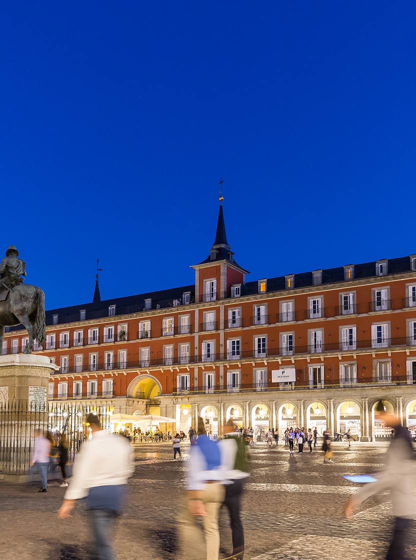 Plaza Mayor, in the historic center of Madrid, at night, with many tourists waljing around the Pestana Plaza Mayor is located