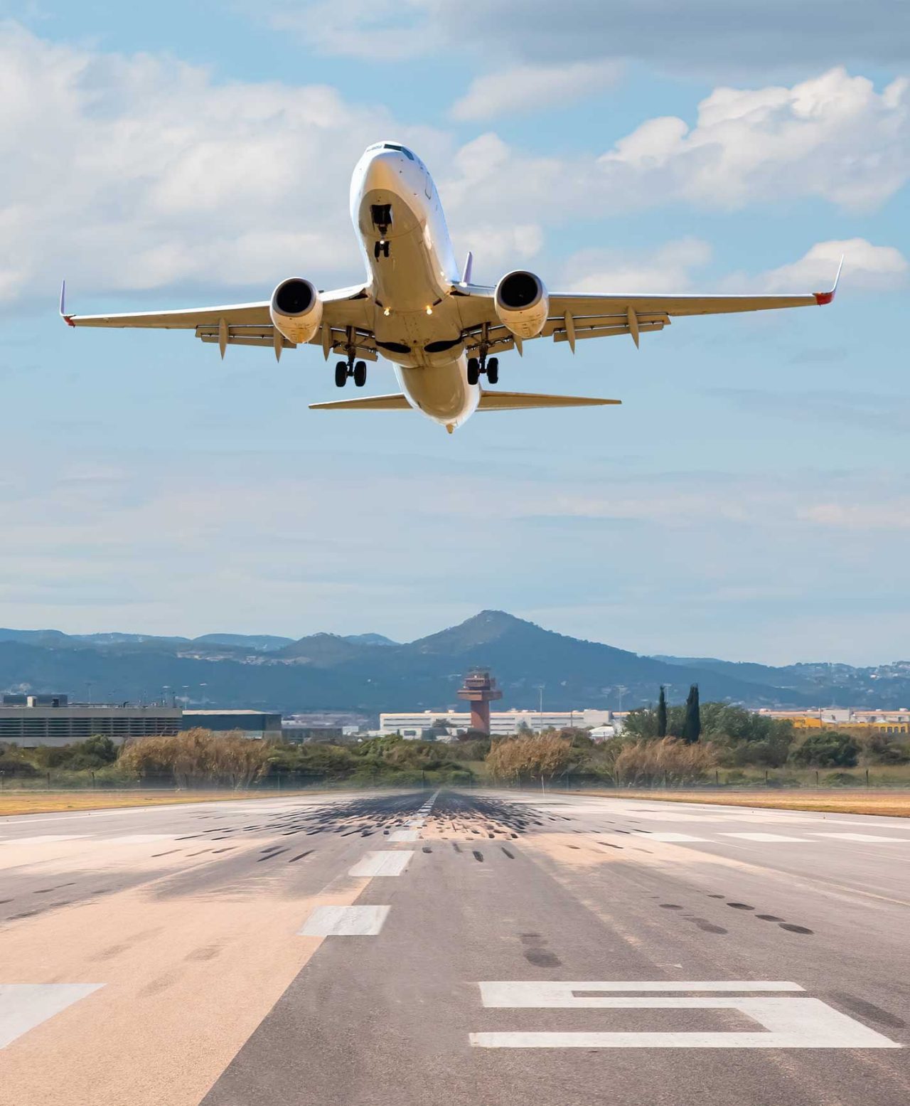 Large commercial plane taking off from an airport runway in Barcelona, with the control tower in the background