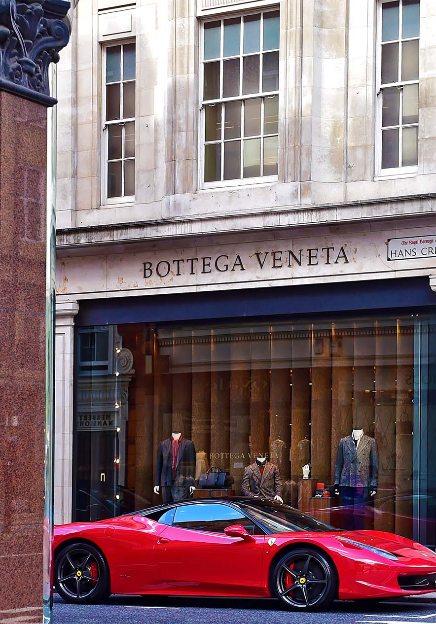Street of luxury shops with shoes and accessories in the window a red Ferrari on the side street