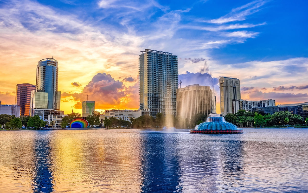 Urban landscape of Orlando at sunset, with a lake and a fountain in the foreground