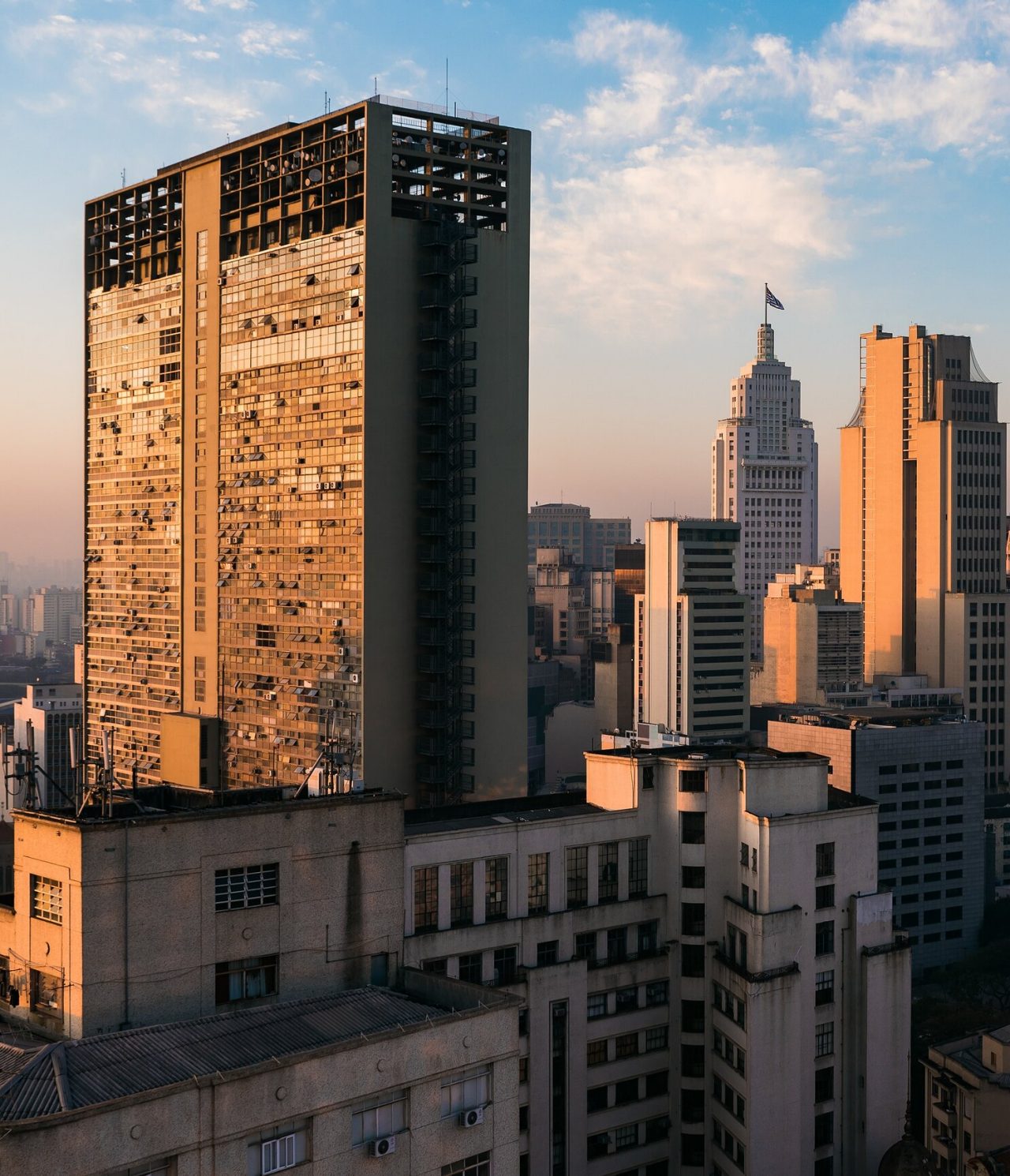 View of several tall buildings in São Paulo, Brazil, with the sun shining on the windows and a blue sky behind