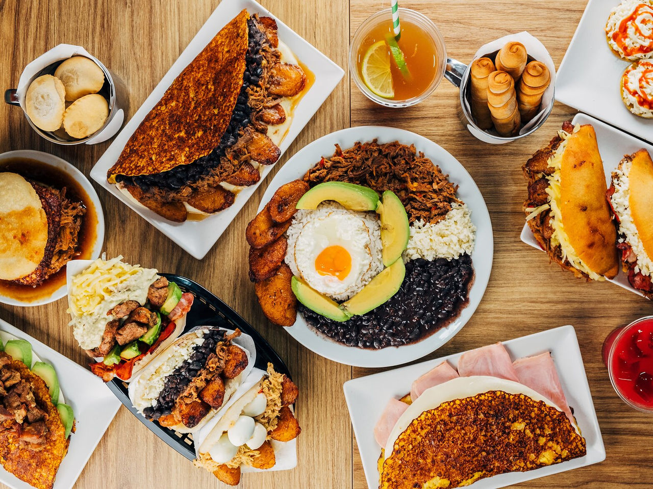 Table full of typical Venezuelan dishes, including arepas, tequeños, and chapachas