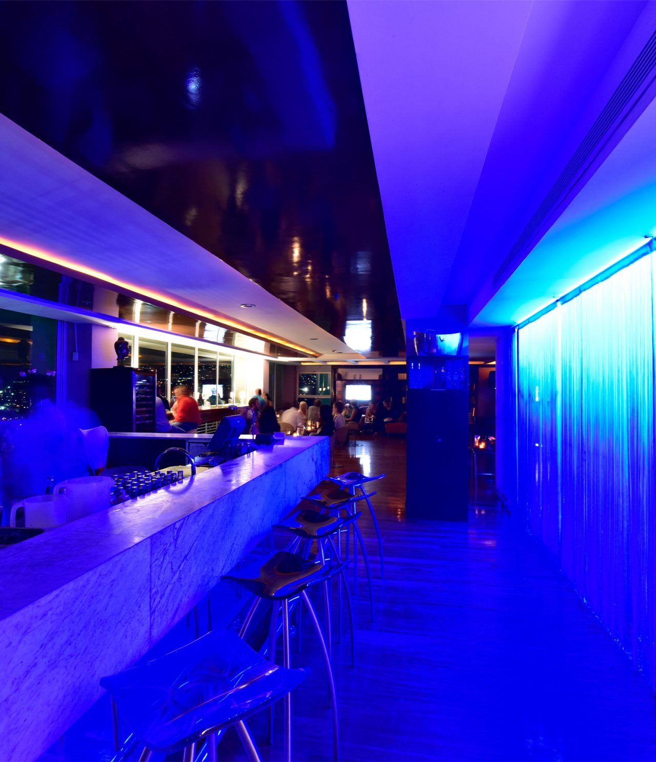 Lounge Ávila has high stools, blue neon lights, and serves alcoholic drinks
