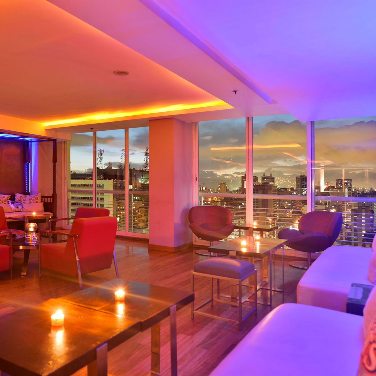 Bar at Pestana Caracas with panoramic city views at sunset, a modern space with sofas and armchairs