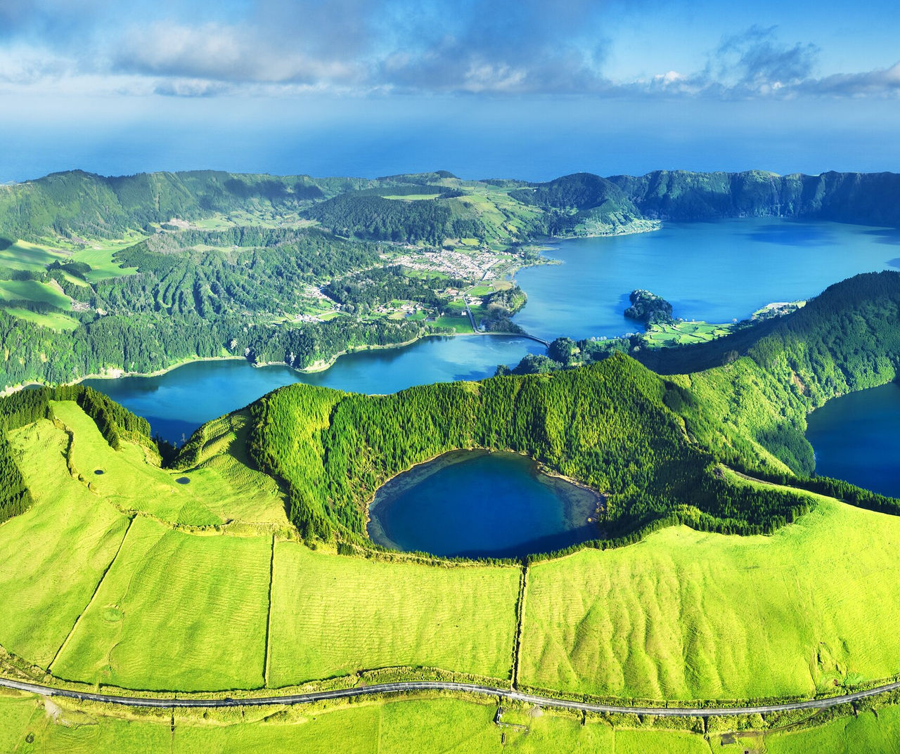 azores hotel featuring an aerial view of green volcanic lakes, rolling hills and a coastal village