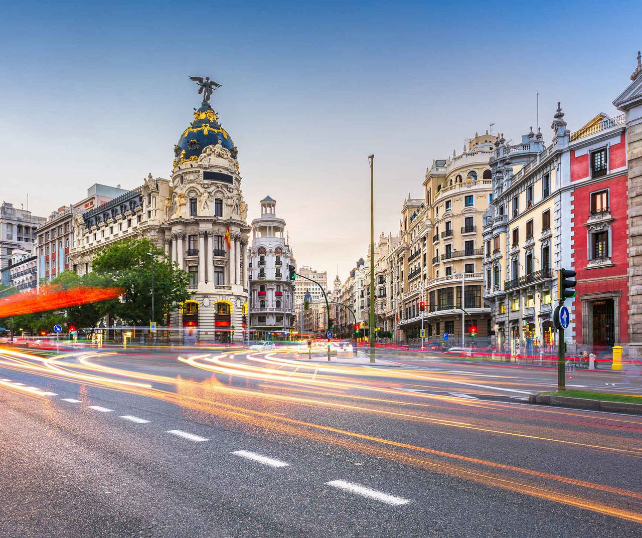 Madrid hotel featuring historic buildings and evening traffic trails along a wide avenue in the city center
