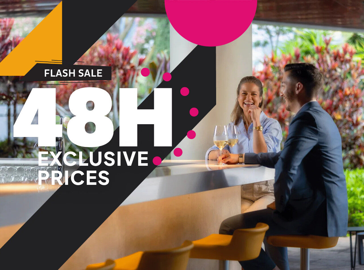 Couple seated at a bright hotel bar beside promotional graphics displaying 48H exclusive flash sale prices