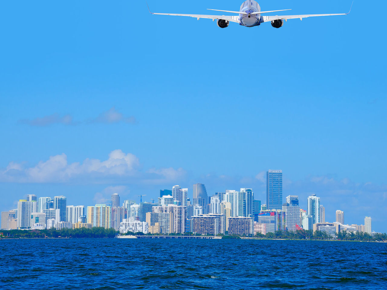 Avión despegando sobre la ciudad de Miami, con edificios altos y cielo azul