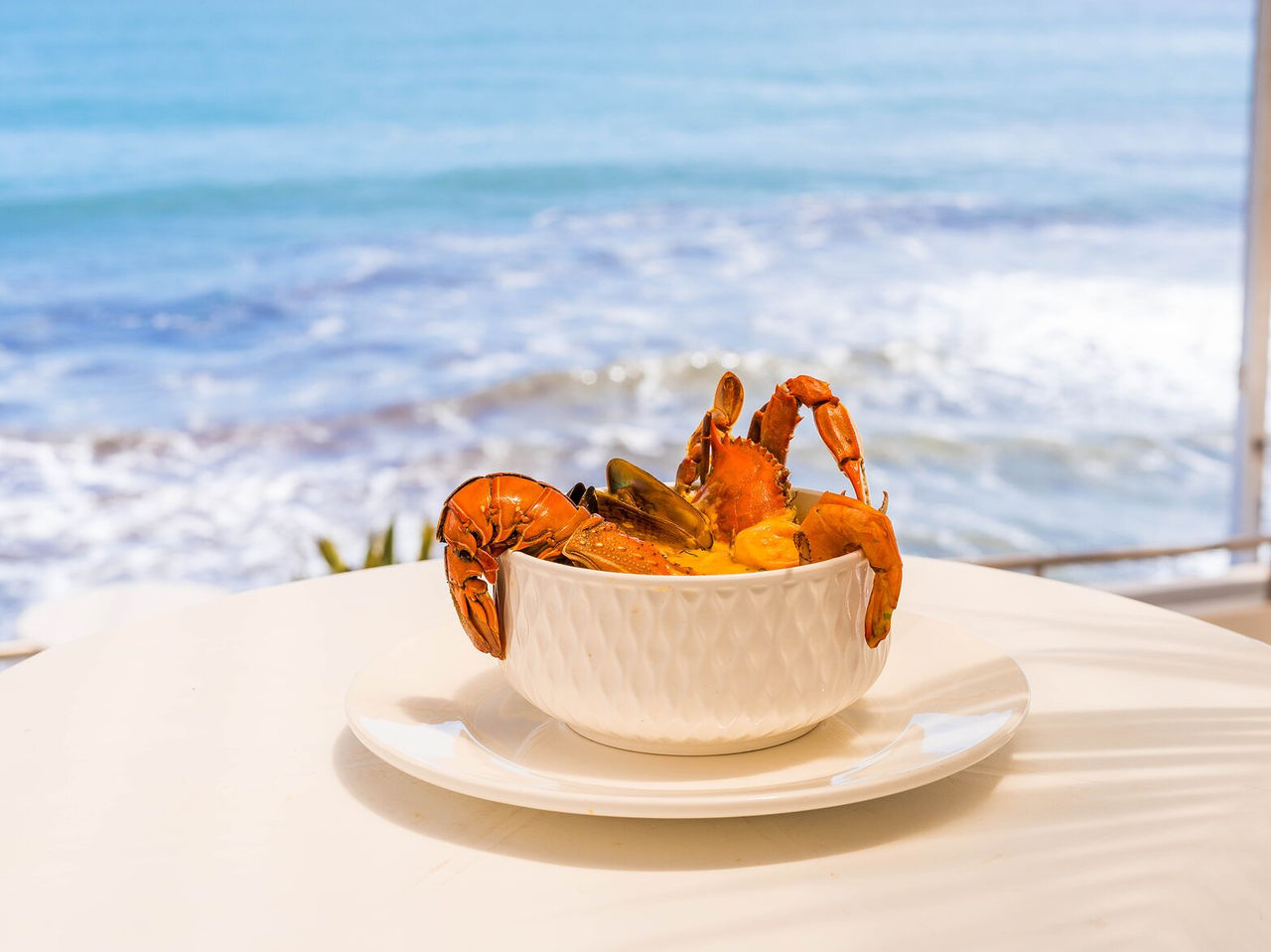 Plato de mariscos destacando camarones y cangrejo, con vista panorámica al océano en Miami