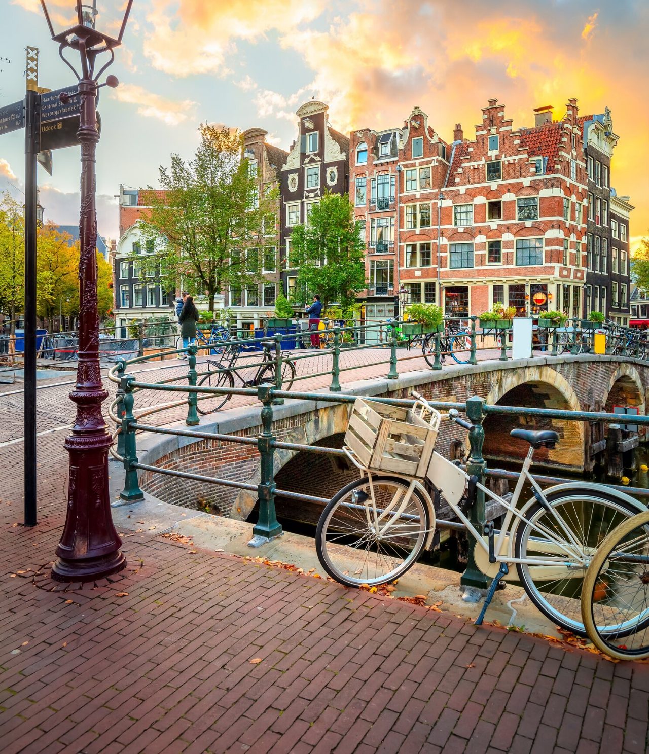 Explora Hoteles en Ámsterdam con vistas a un canal con bicicletas y casas históricas al atardecer urbanas