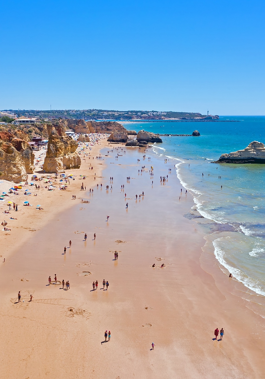 Visita la Playa da Rocha con varias rocas en la arena que se encuentran con el agua azul del Algarve