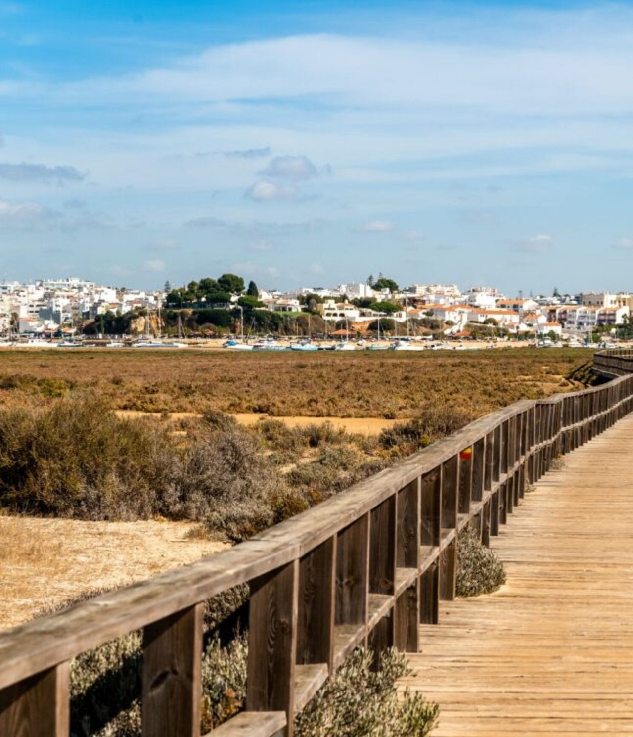 Explora Hoteles en Alvor, Algarve con vistas a una pasarela de madera junto a dunas y casas costeras