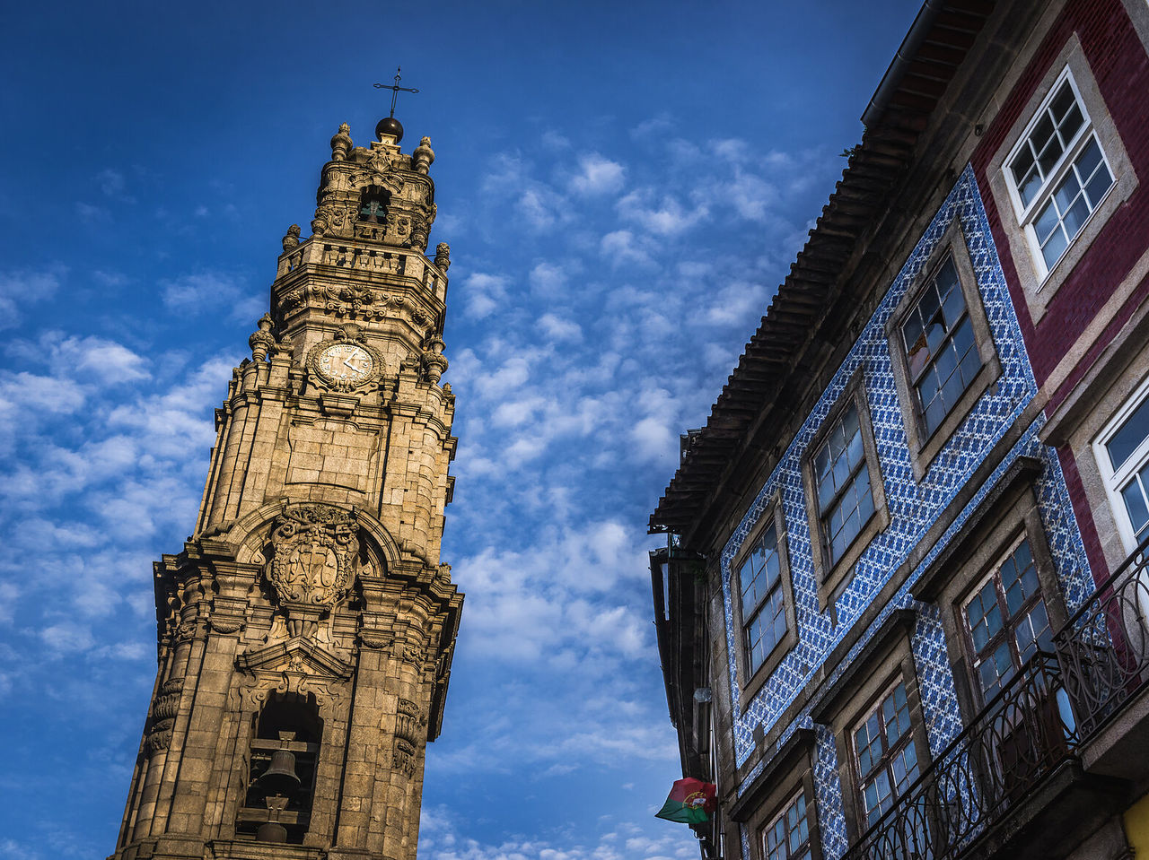 Imponente Torre de los Clérigos destacándose contra el cielo azul, mientras un edificio vecino muestra la arquitectura típica
