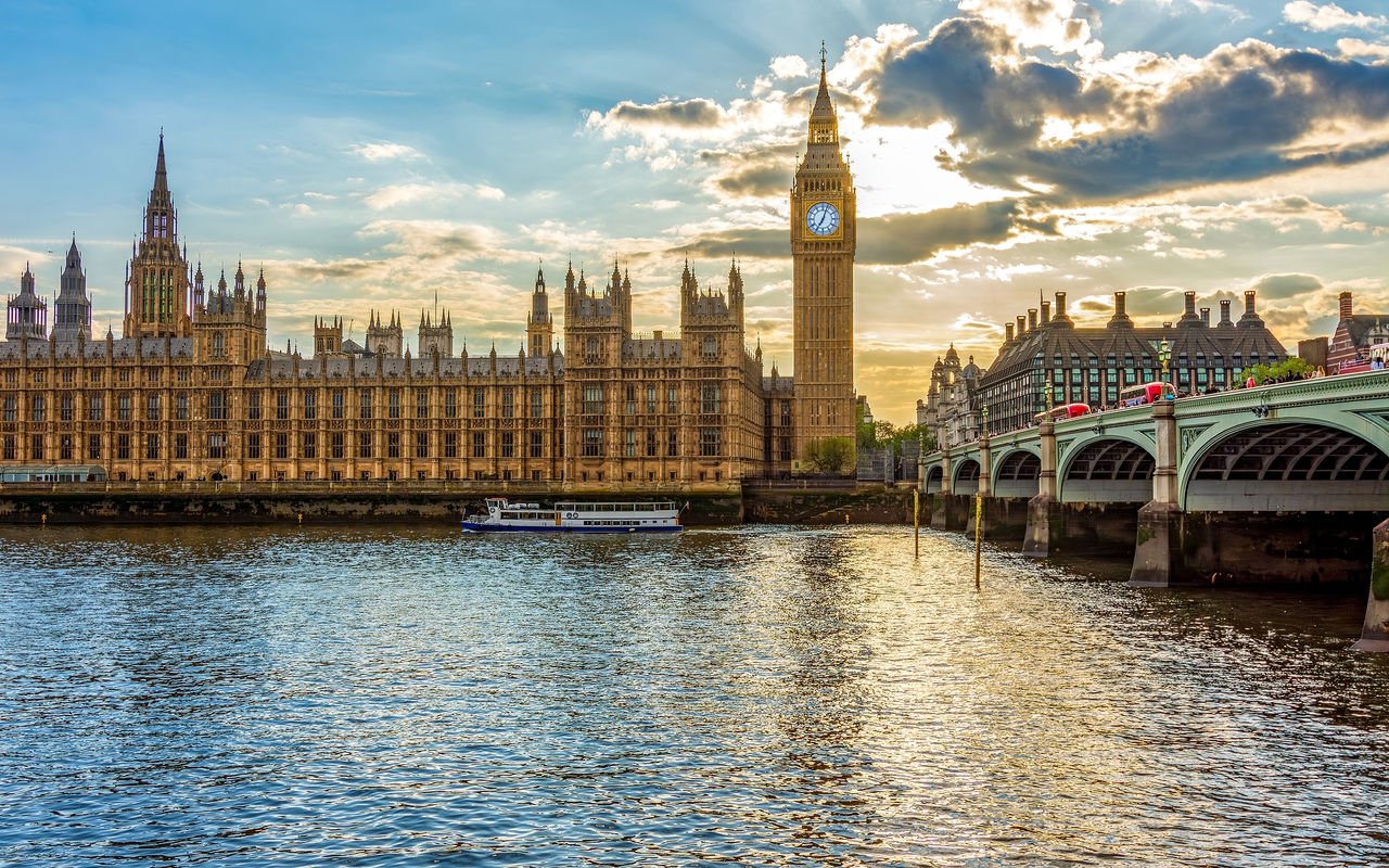 Vista panorámica del Palacio de Westminster, en Londres, junto al emblemático Big Ben, con el río Támesis en primer plano.