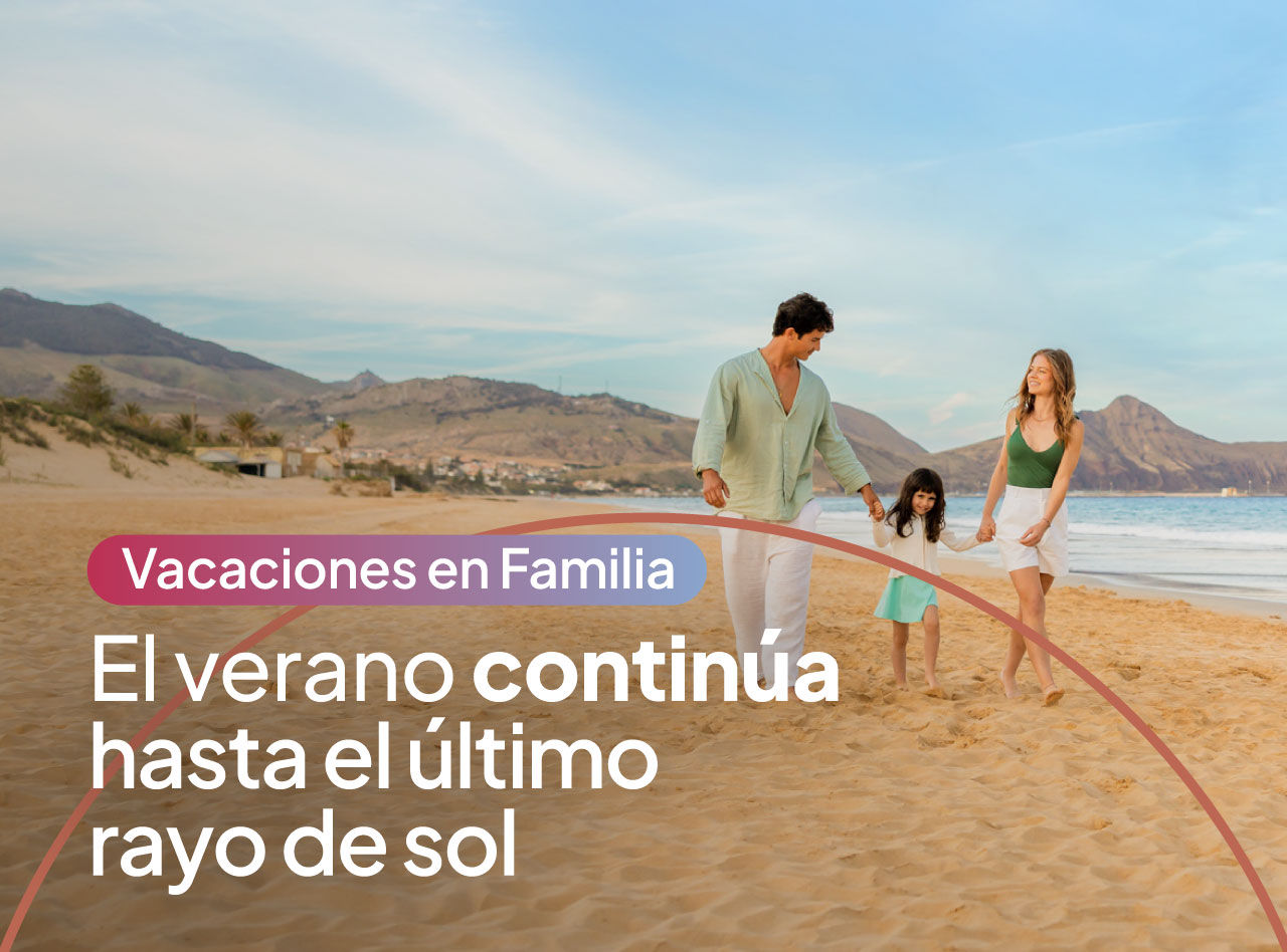 Familia caminando de la mano por una playa de arena junto al mar con montañas y cielo despejado al atardecer