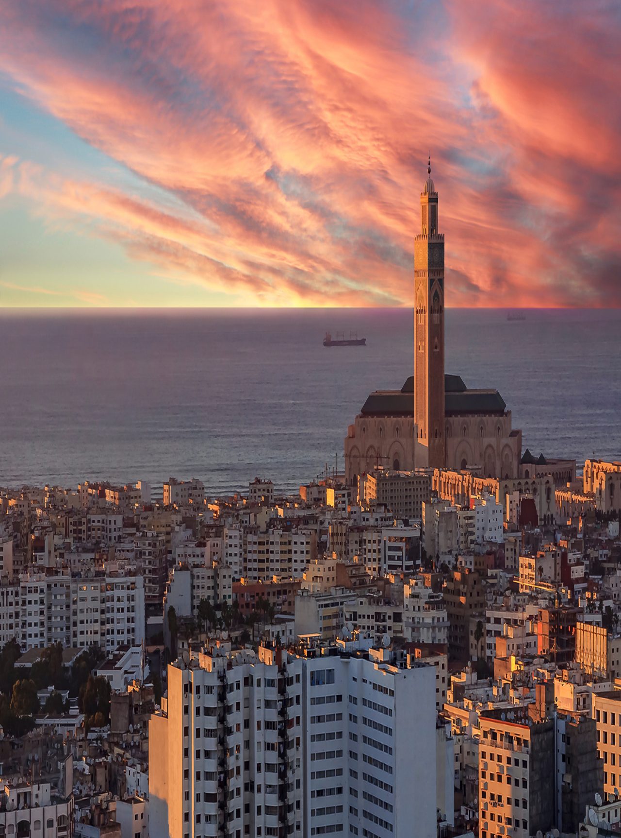 Vue aérienne de Casablanca, coucher de soleil illuminant des bâtiments, ciel à l'horizon, mer et tour