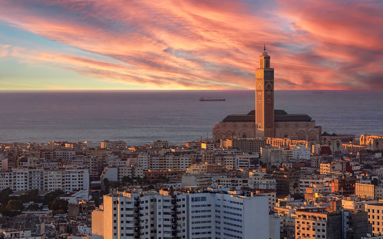 Vue aérienne de Casablanca, coucher de soleil illuminant des bâtiments, ciel à l'horizon, mer et tour