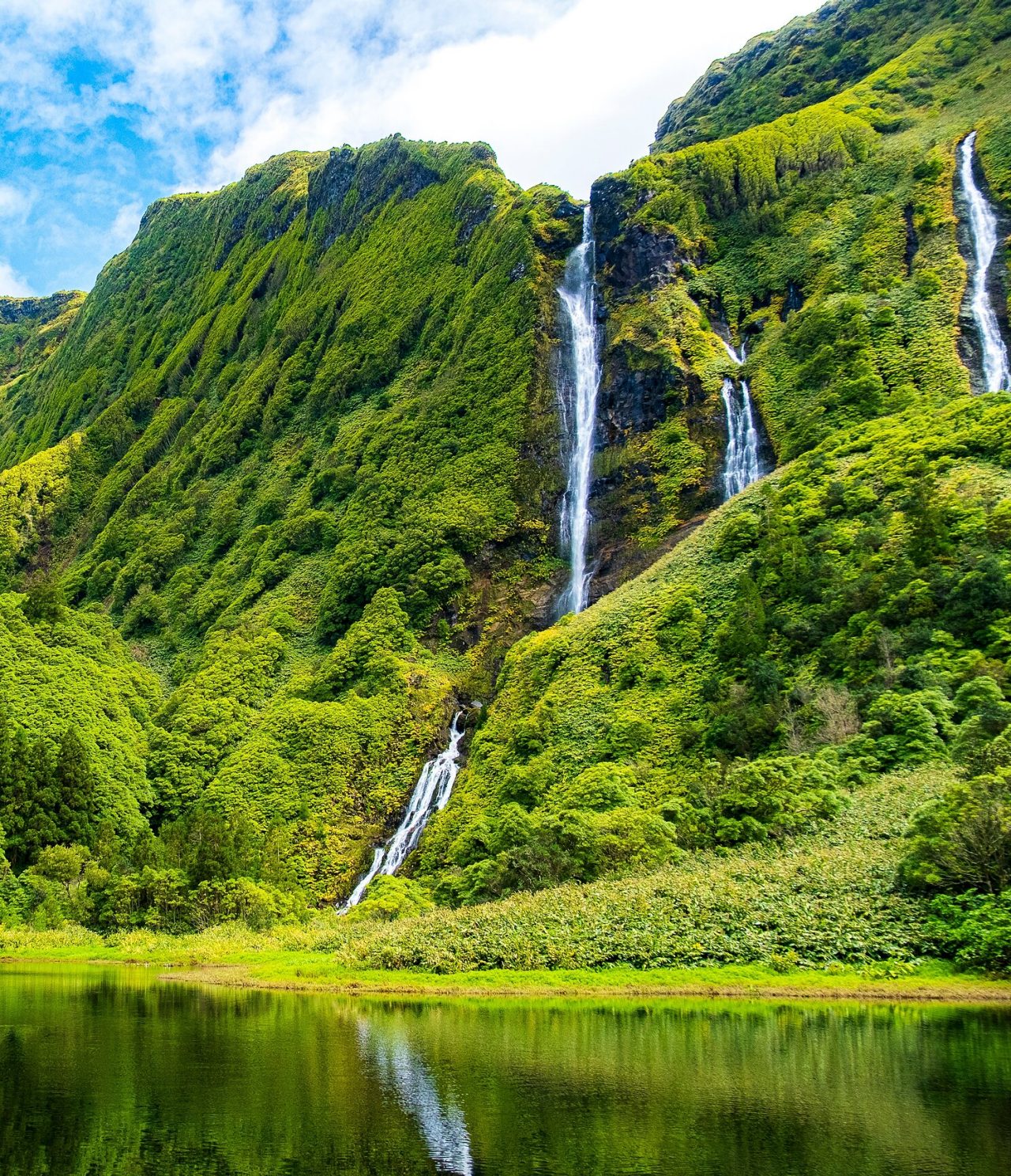 Cascade éblouissante entourée de montagnes couvertes de végétation verte sur l'île de Flores, Açores