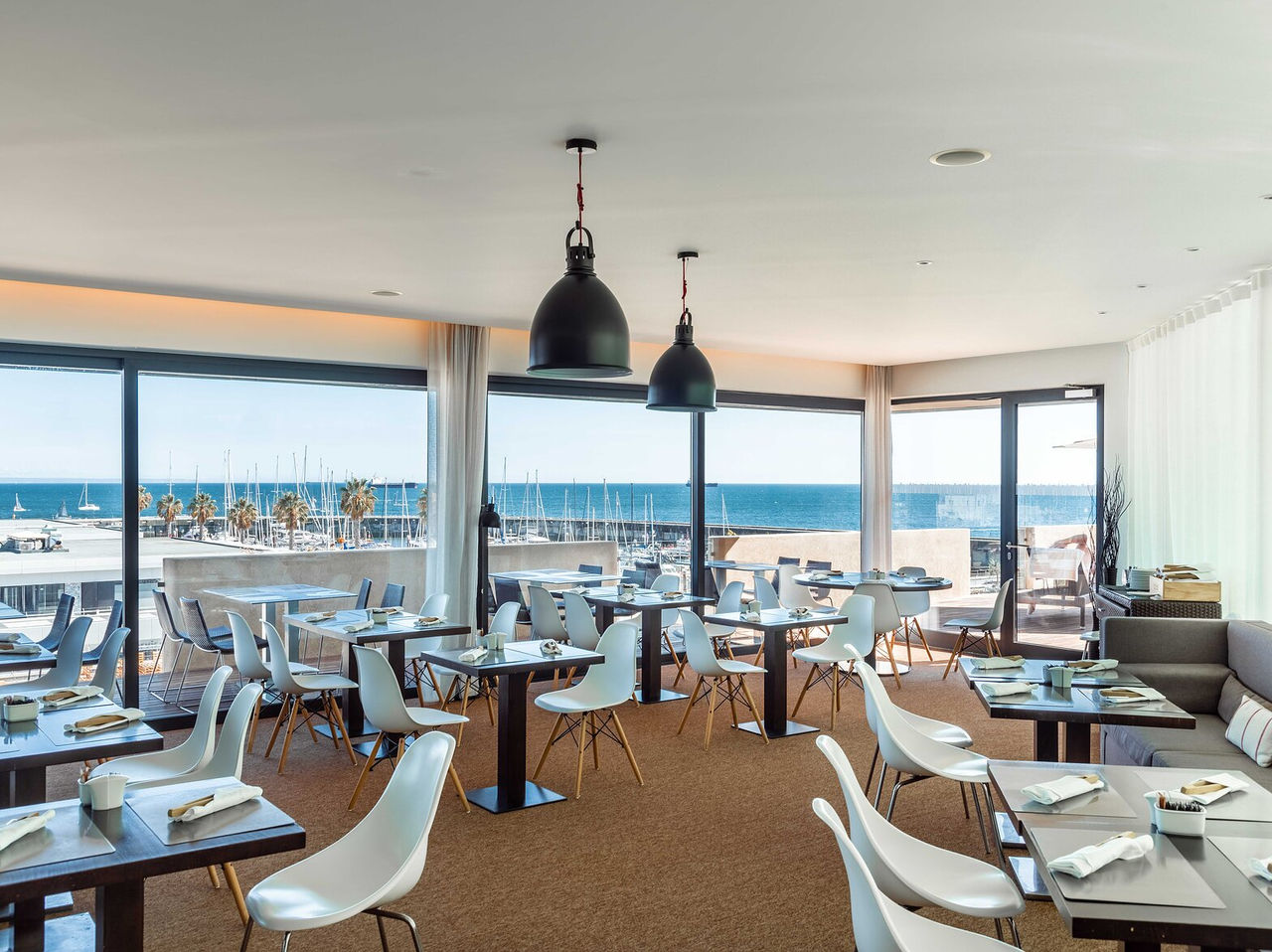 Le restaurant Maris Stella de l’hôtel 5 étoiles à Cascais a plusieurs tables, chaises et vue sur le port de Cascais