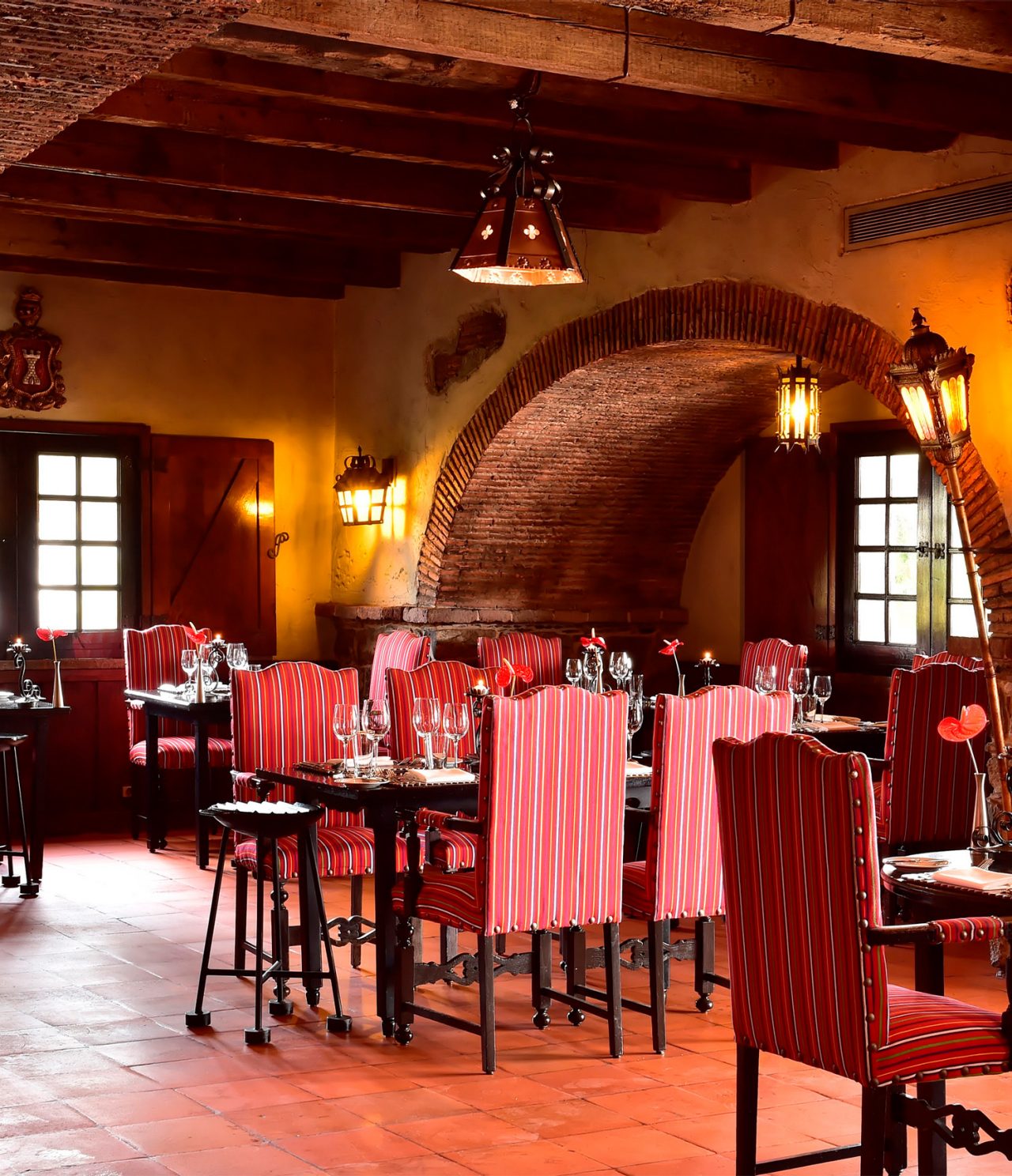 Le restaurant Taverna Grill de l’hôtel à Madère a un espace spacieux avec des chaises rouges, des tables et des lampes