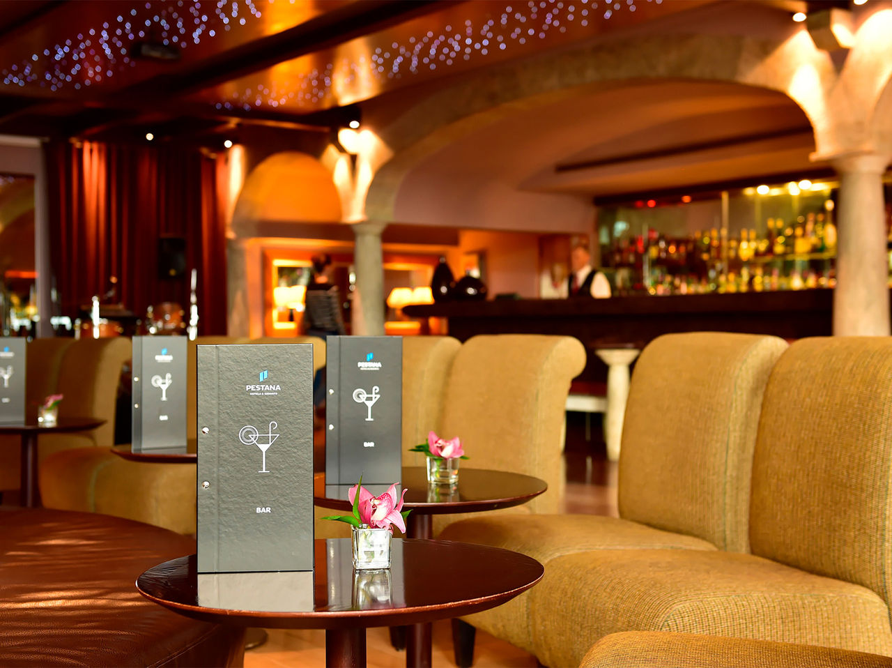 Le bar Taverna de l’hôtel 5 étoiles à Madère a des bancs avec des tables, des menus et un vase de fleurs