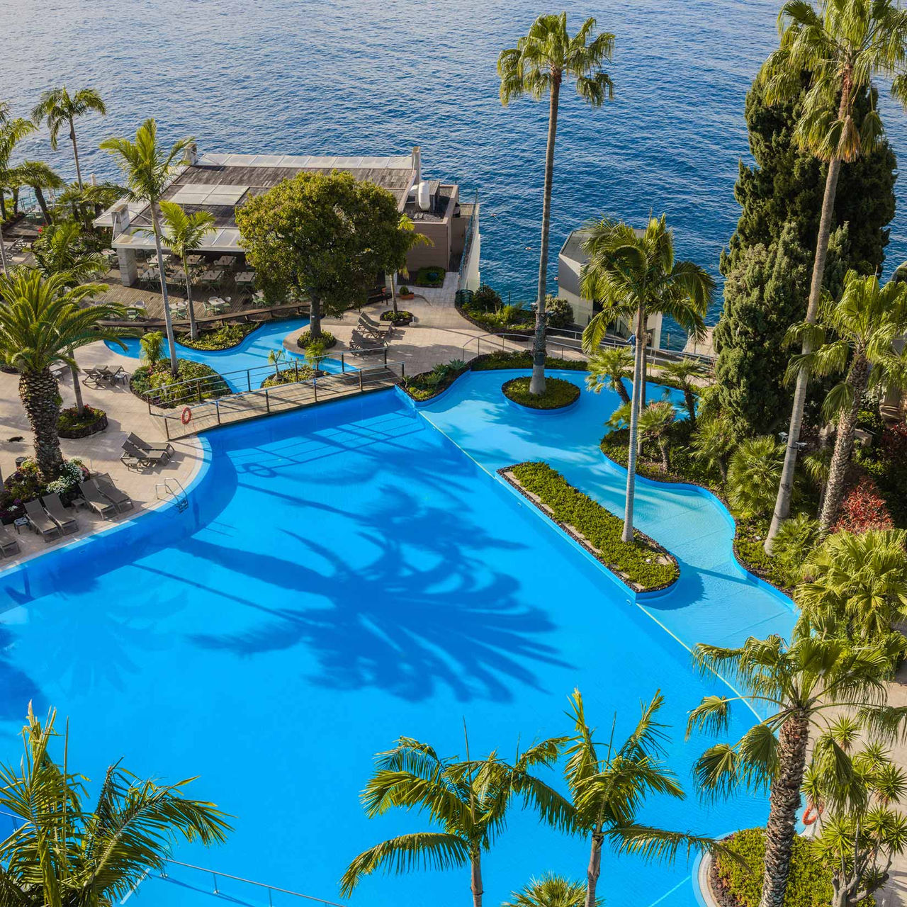 Pestana Carlton Madeira, Hôtel 5 Étoiles à Madère avec grande piscine bordée de palmiers face à l’océan
