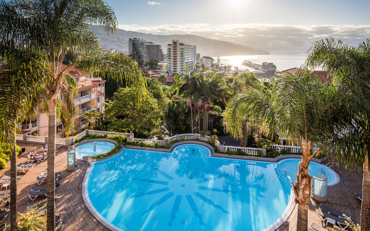 Vue aérienne de la piscine du Pestana Miramar, un hôtel à Madère près de la plage, entouré de palmiers