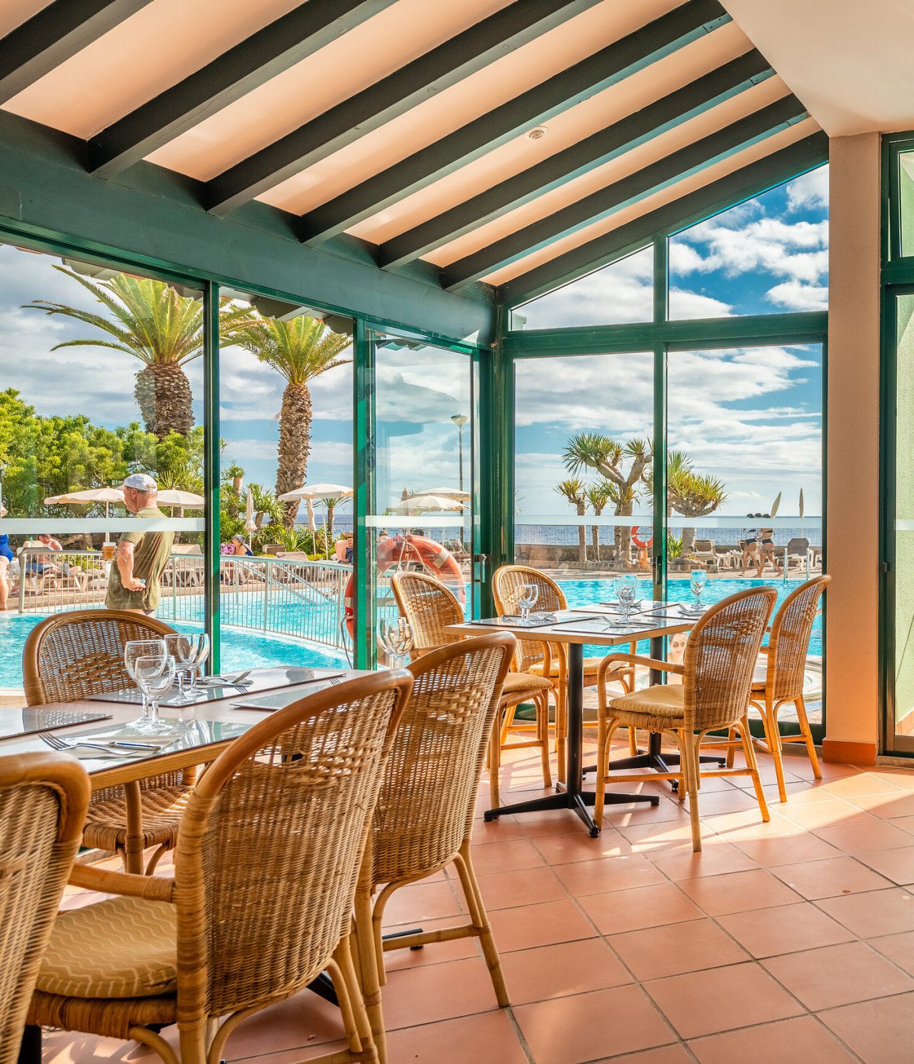 Le restaurant Arlequim, de l'hôtel 5 étoiles à Funchal, Madeira, a des tables avec chaises en paille et vue sur piscine