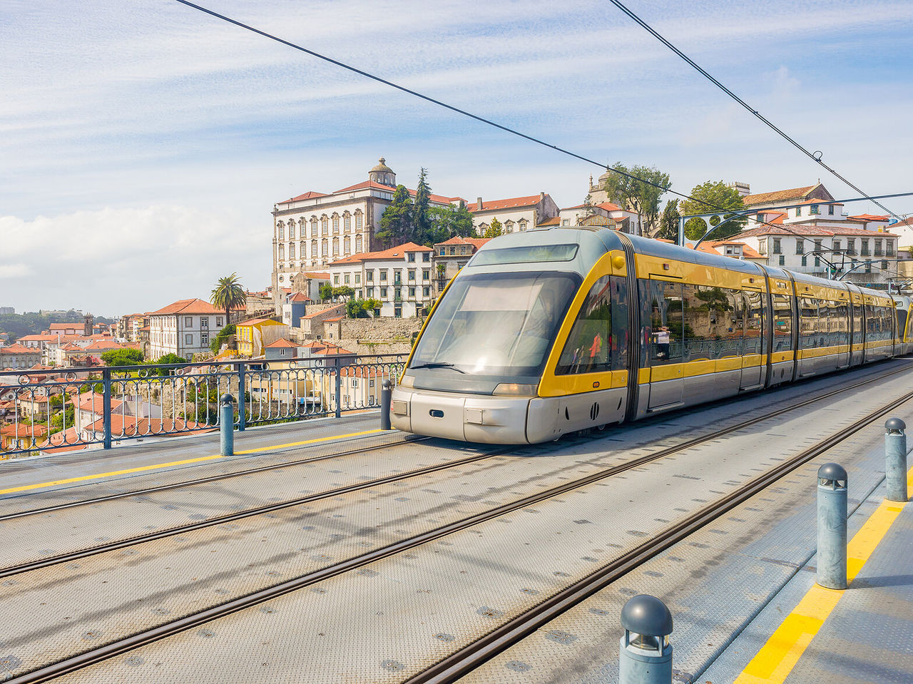 Vue d'un tramway jaune moderne avec la ville historique de Porto en arrière-plan, avec des bâtiments hauts et colorés