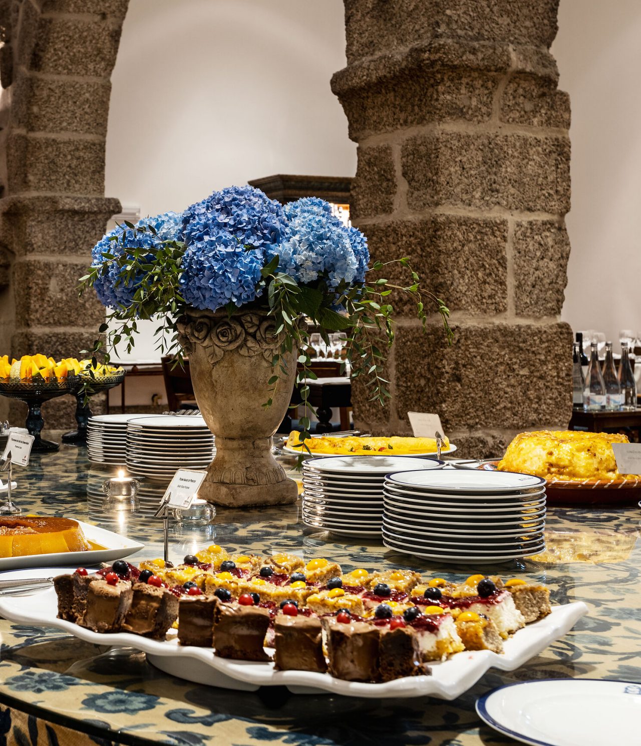 Table décorée avec une variété de sucreries, des gâteaux et tartes aux fruits, dans une pièce avec des meubles anciens