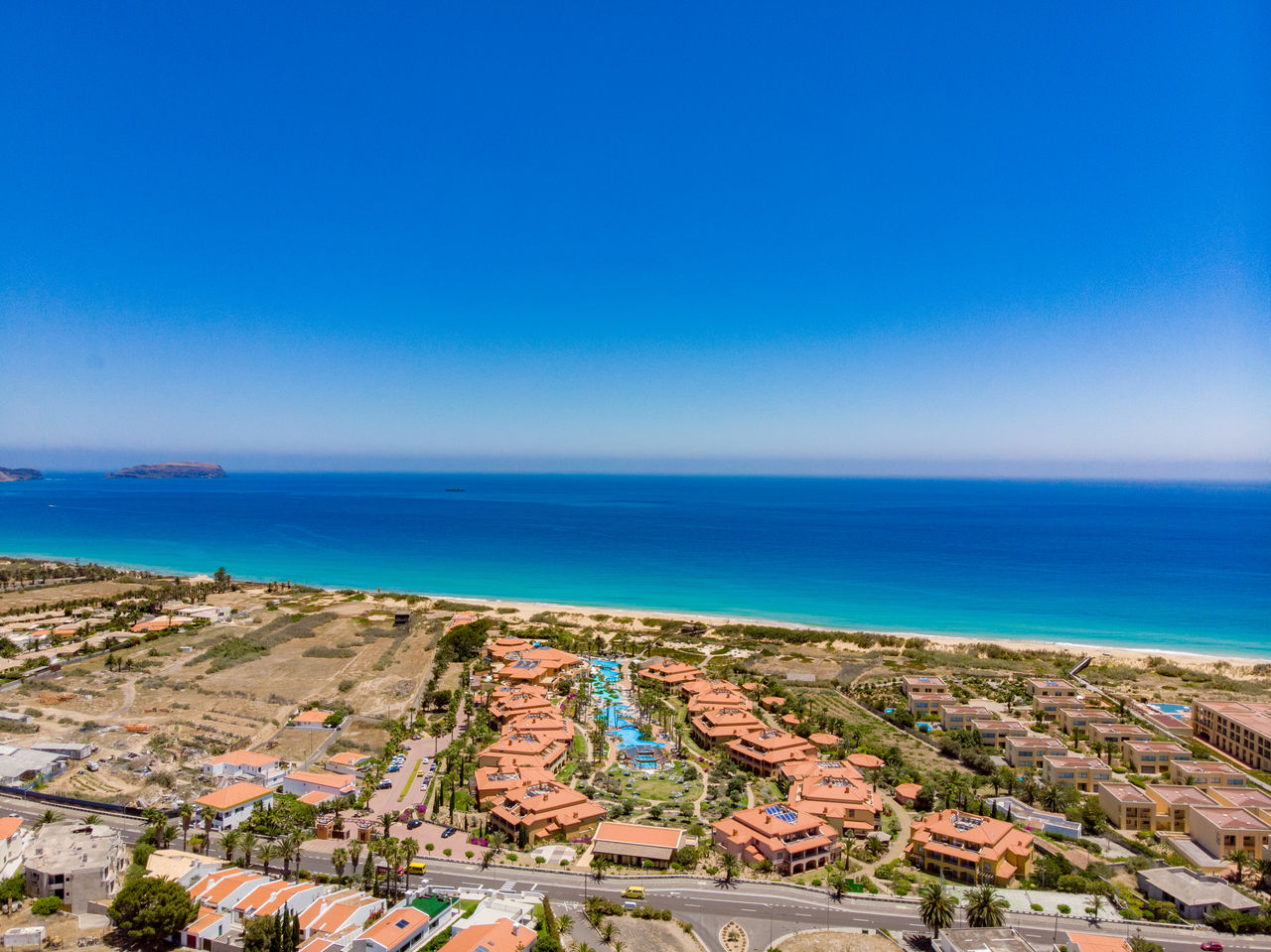 Vue aérienne du Pestana Porto Santo, avec ses divers bâtiments et piscines, face à une mer bleu turquoise