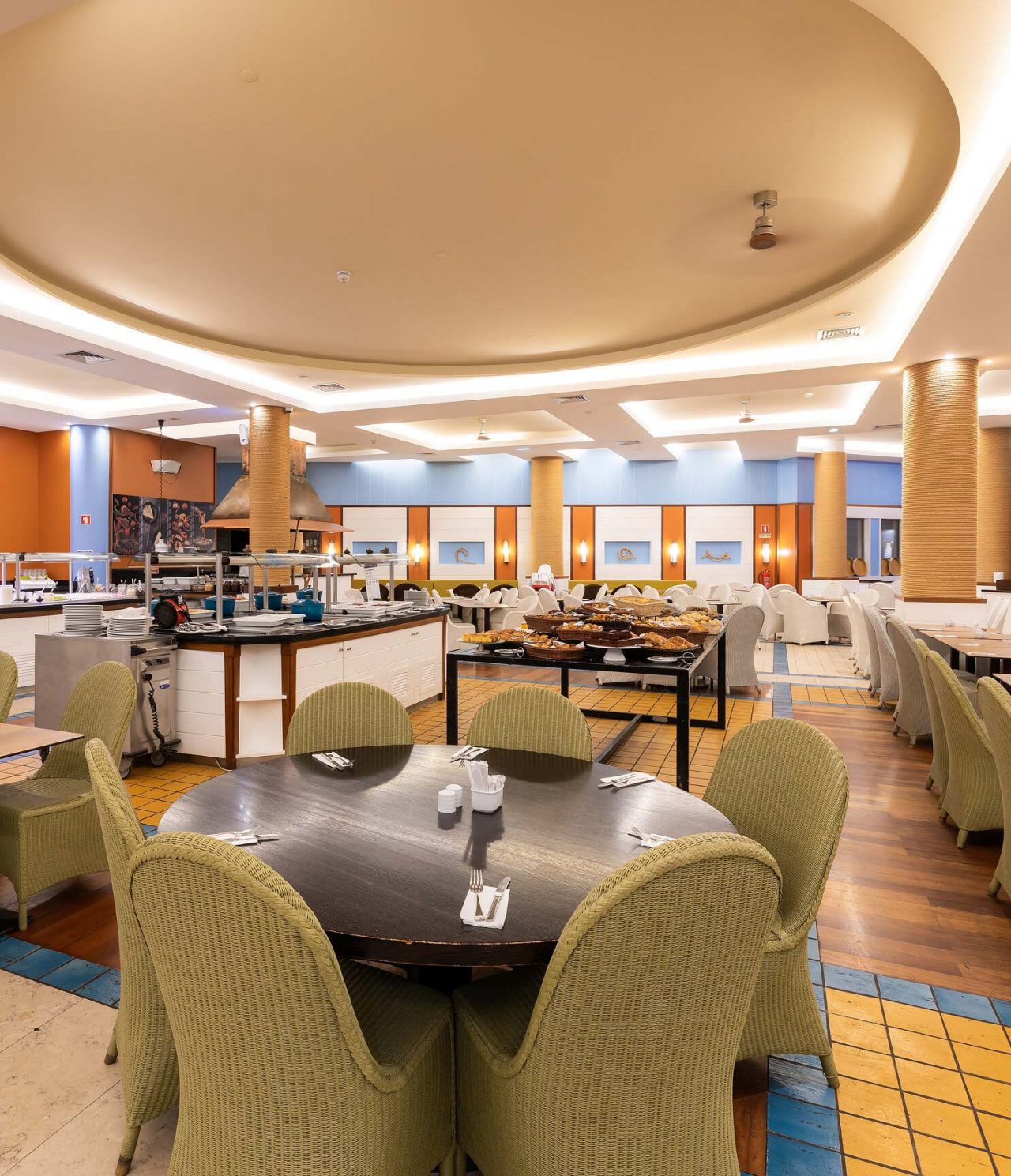 Le restaurant Marés du Resort 5 étoiles à Porto Santo a un grand espace avec des murs jaunes et des chaises vertes.