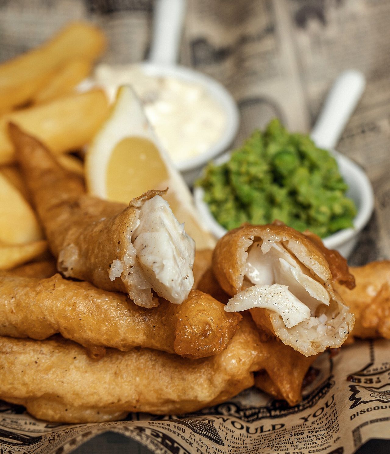 Poisson frit avec des frites, du citron, de la sauce blanche et de la pâte verte, un plat typique de Londres