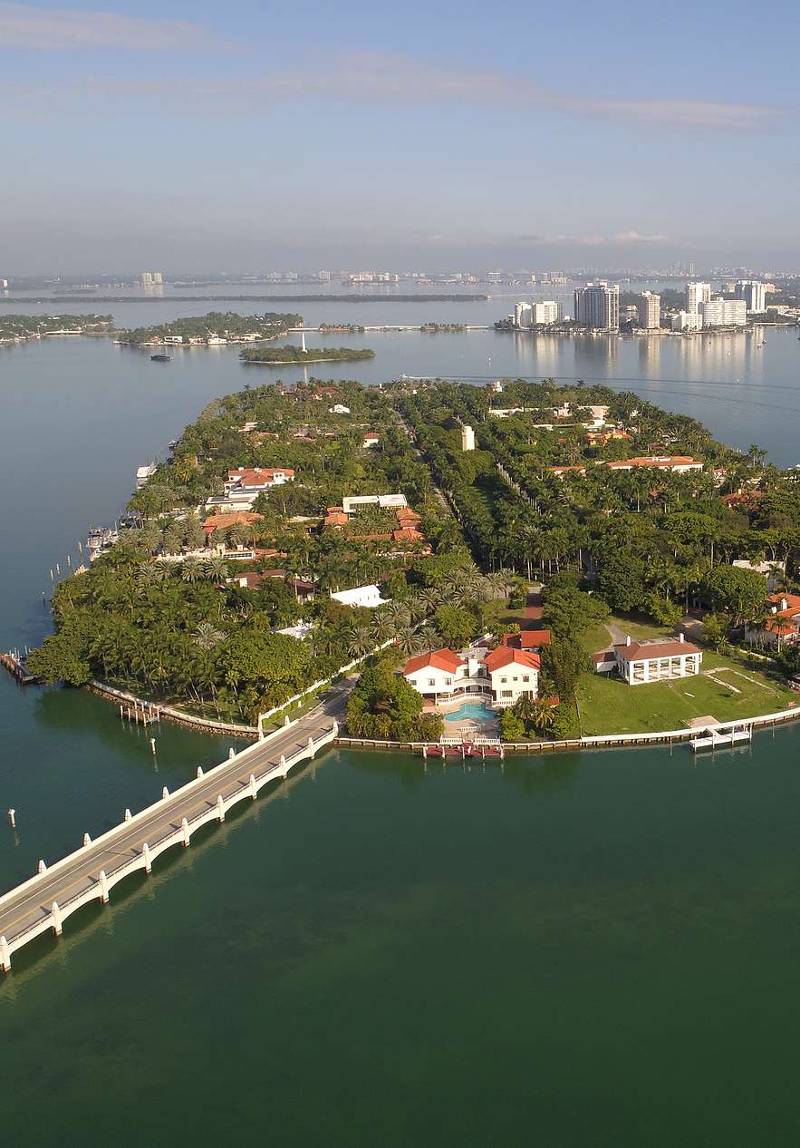 Vue aérienne de Star Island à Miami, avec des maisons et une végétation intense, une passerelle reliant l'île à la ville