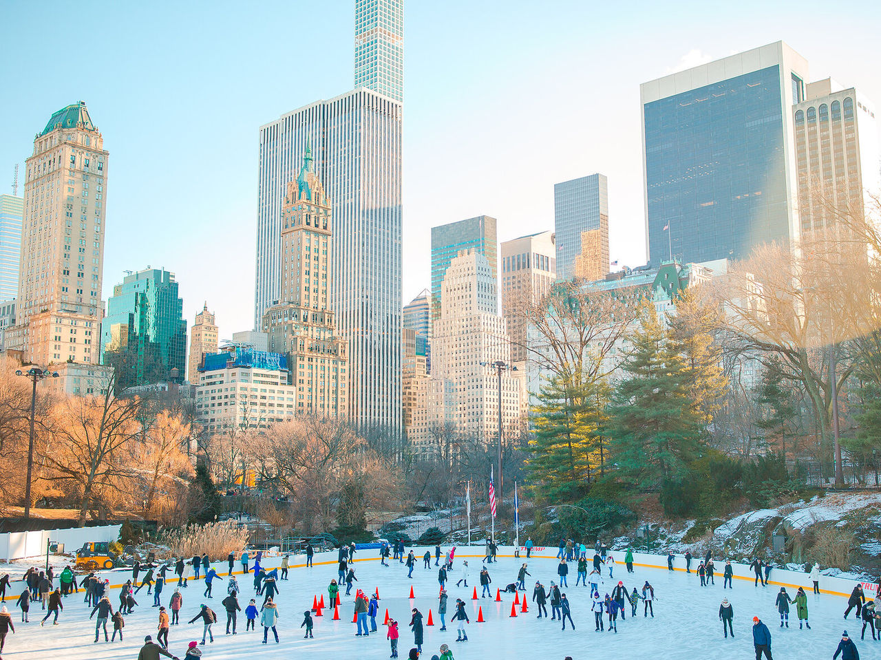 Des gens patinant sur la glace à Central Park, avec la ligne d'horizon de la ville en arrière-plan