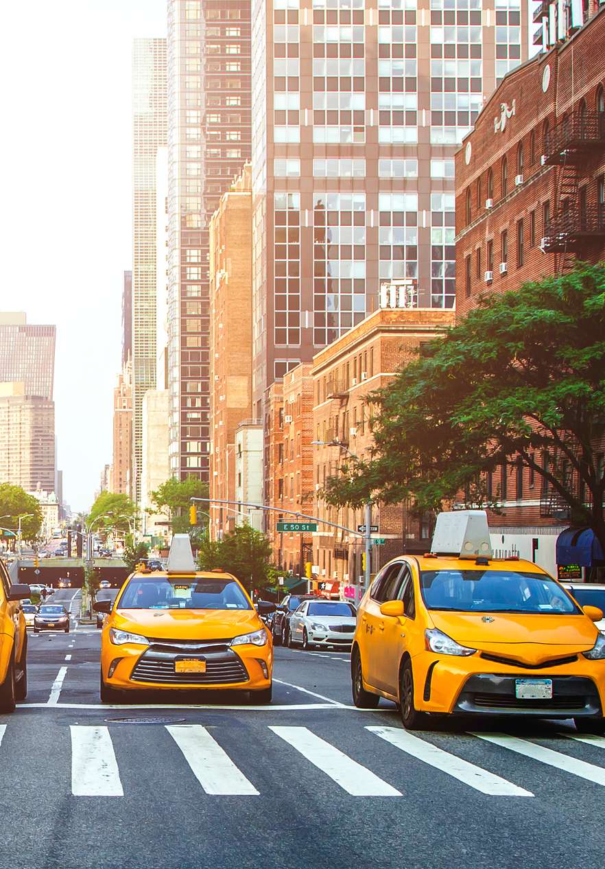 Vue de Times Square, avec des taxis jaunes, un bus scolaire, et des gens traversant la rue