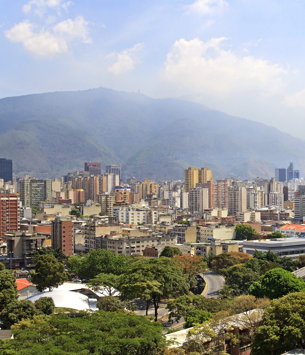 Vue aérienne panoramique de Caracas, avec plusieurs hauts bâtiments, quelques constructions modernes et de la végétation