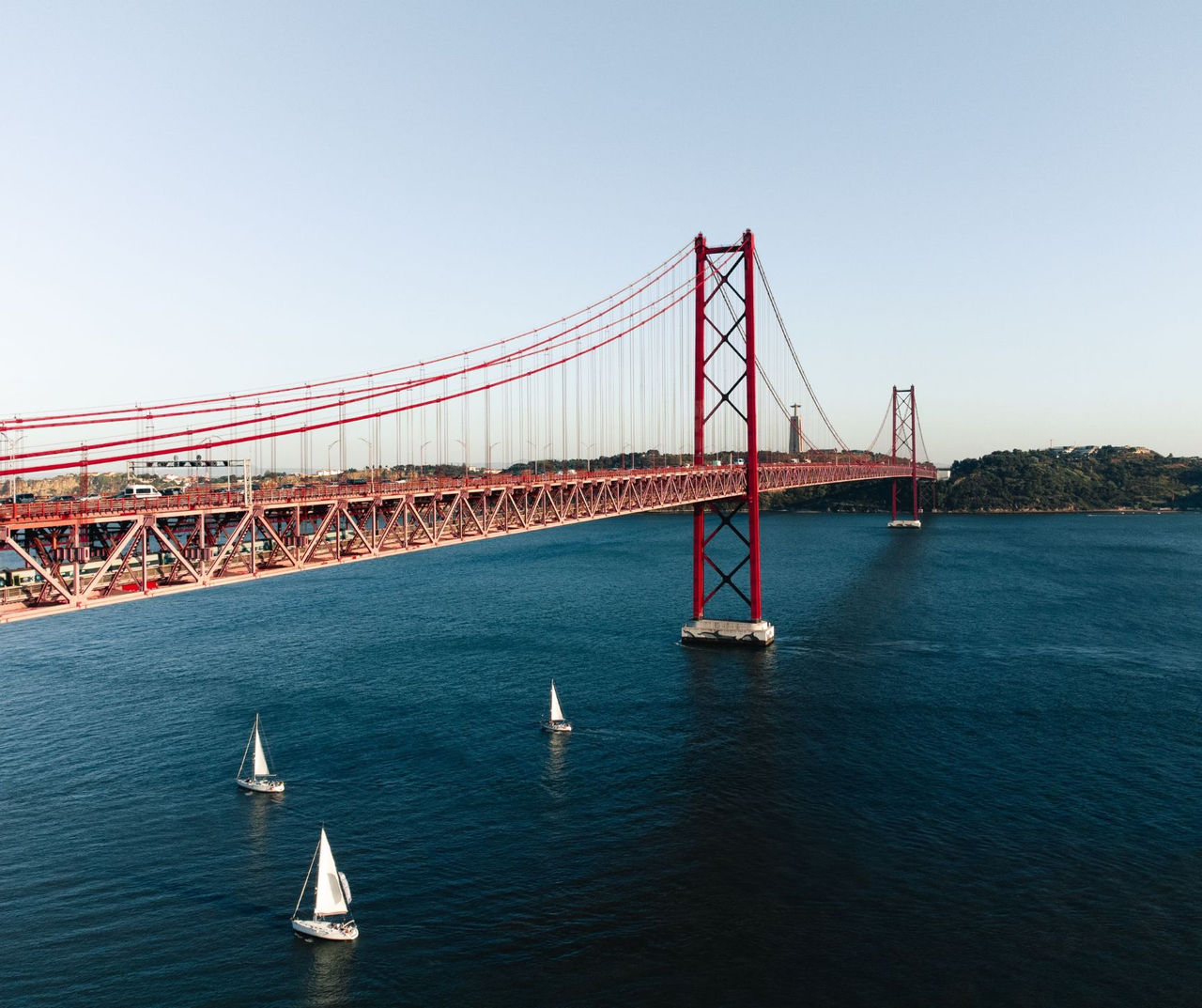 Lisbon hotel featuring the red suspension bridge across the river with several white sailboats below
