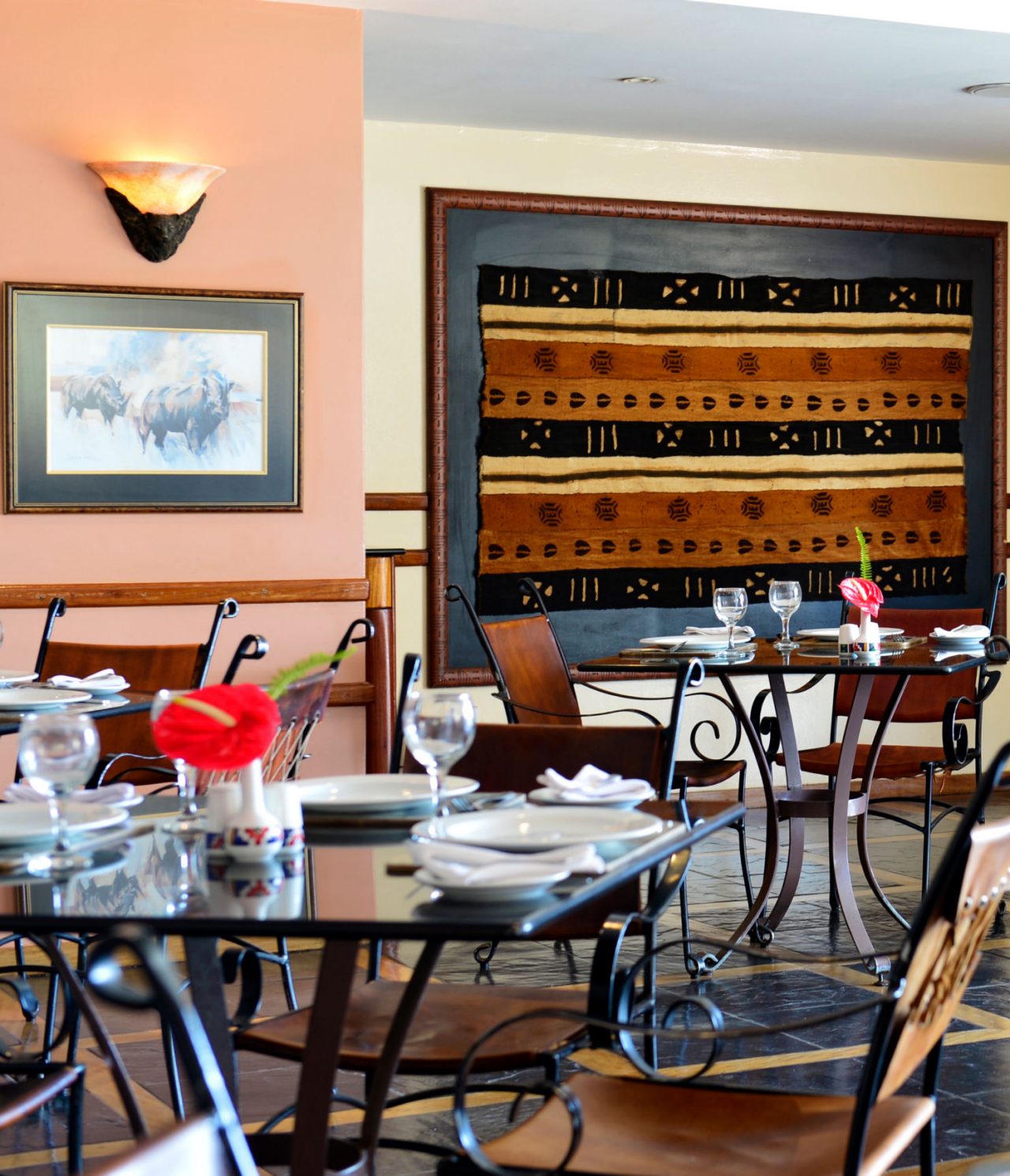 Het restaurant Monomotapa, van het 4-sterrenhotel in Maputo, heeft verschillende tafels met een rode bloem en stoelen