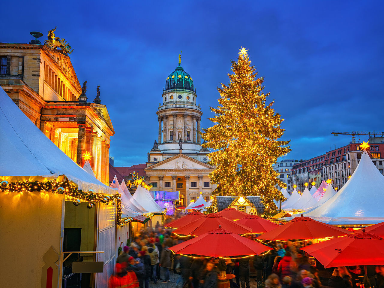Franse Kathedraal van Berlijn verlicht, met een torenhoge kerstboom in het midden van een markt omgeven door kraampjes