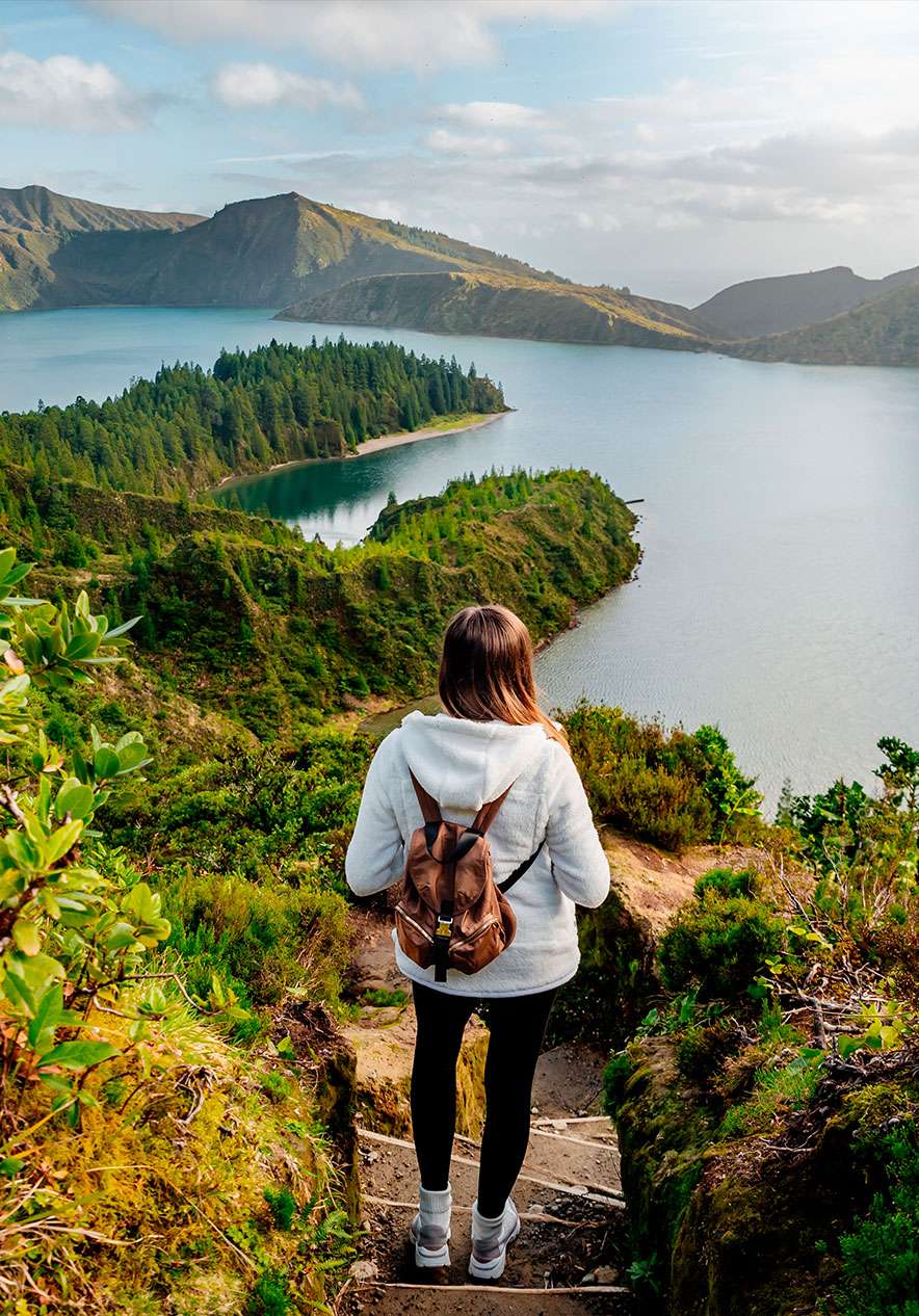 Meisje met een rugzak, omhoog klimmend via de trappen naar de prachtige Lagoa do Fogo, omringd door natuur