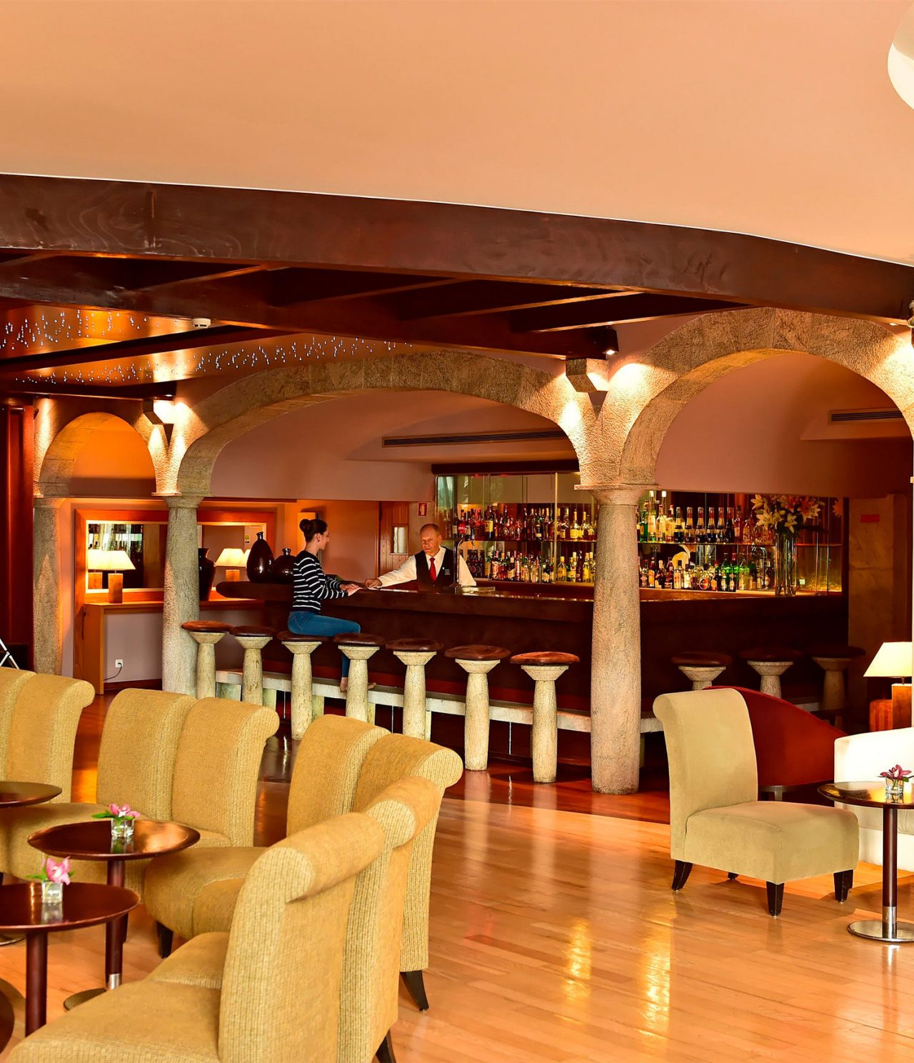 De Taverna-bar, in het hotel in het centrum van Funchal, Madeira, heeft krukken met tafels met menu's en een bloemenvaas