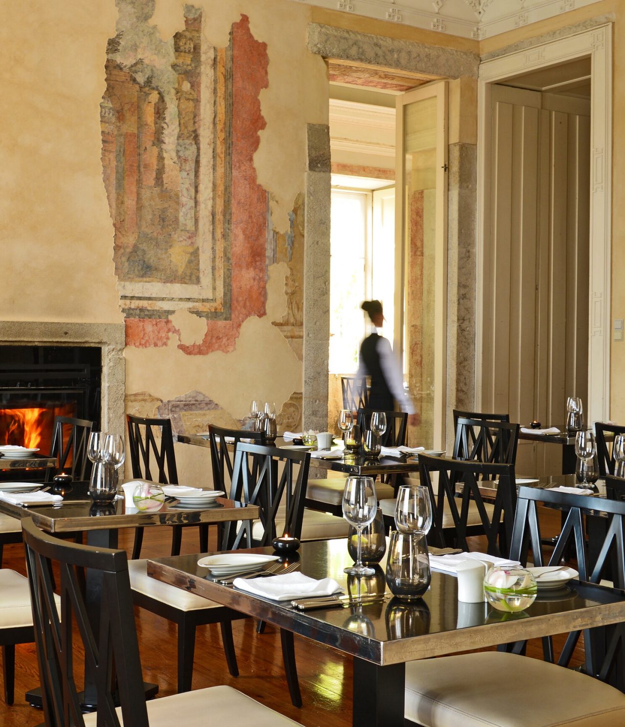 Restaurante do Pestana Palácio do Freixo, Hotel no Rio Douro com Spa e Piscina, com mesas elegantes, copos de cristal e um funcionário ao fundo junto a uma parede com frescos antigos
