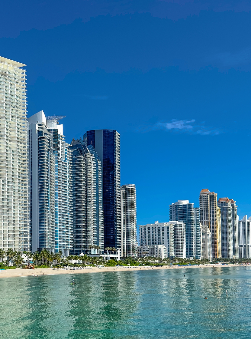 Uitzicht over de kustlijn van Miami Beach met moderne wolkenkrabbers aan zee, lichte zandstranden en kristalblauw water