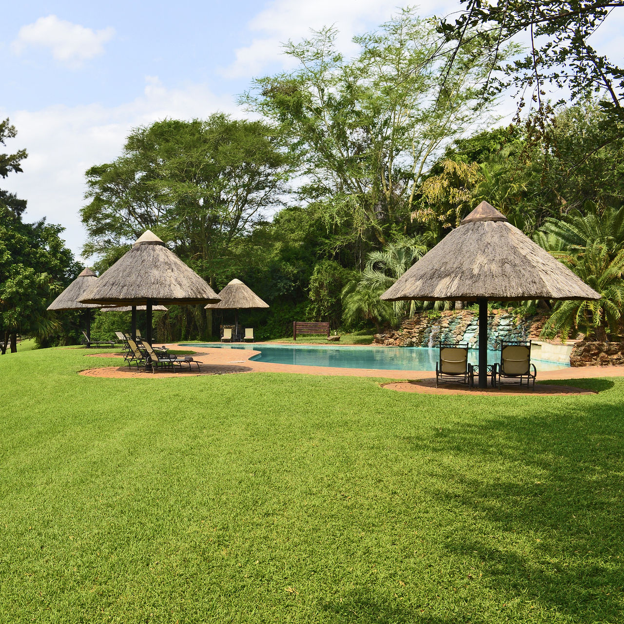 Jardim, piscina exterior e espreguiçadeiras do Pestana Kruger Lodge, um hotel 4 Estrelas no Kruger Park